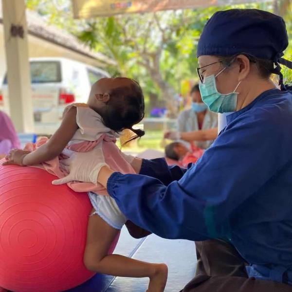 A woman works with a young child on a Swiss ball