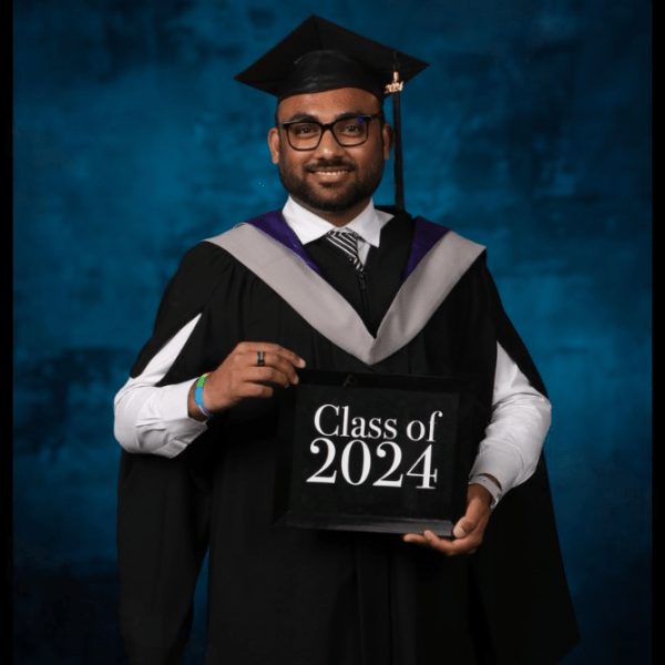 Ashutosh Mishra in his grad regalia holding a Class of 2024 sign.