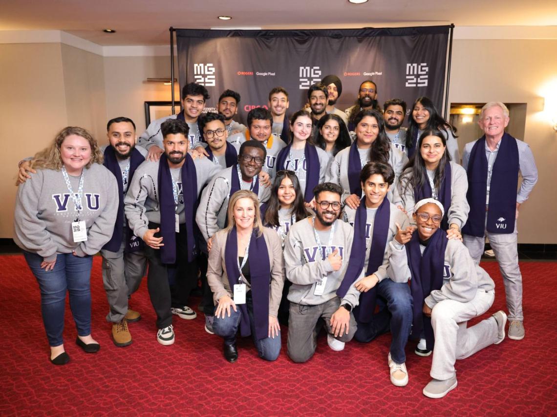 Group photo of people standing on a red carpet wearing blue scarves with the VIU logo on them