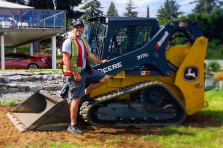 Jesse Anderson standing outside in front of one of his machines on a sunny day.