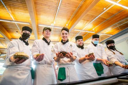 Culinary arts students hold different seafood items