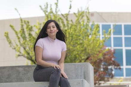 Student sitting on stairs, smiling at camera