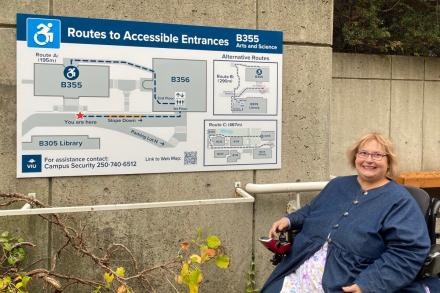 A woman poses beside a wayfinding sign at VIU's Nanaimo campus