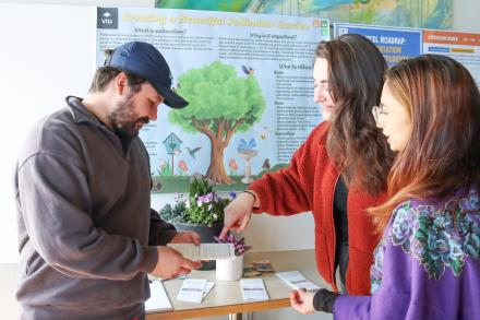 Three students next to a poster explaining research