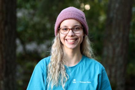 Portrait photo of Kennedy Ordano smiling at the camera with a forest background