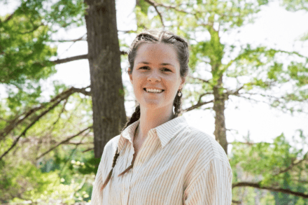 Laura Hutchinson smiling at the camera with trees in the background.