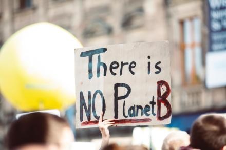 Hands holding a sign that reads: There is no Planet B