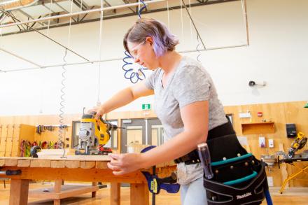 Female cutting a board in carpentry shop