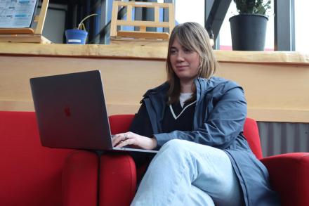 Young woman sitting on a red couch looking at a laptop